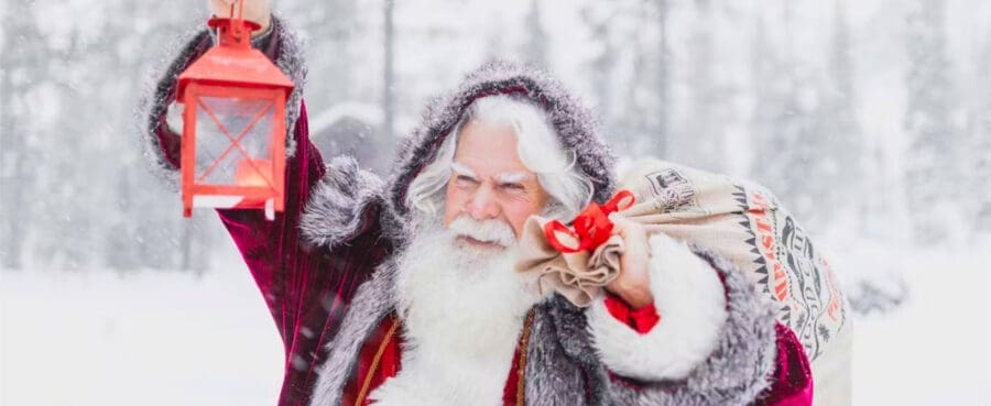 Santa in Lapland holding a lamp and his sack of presents