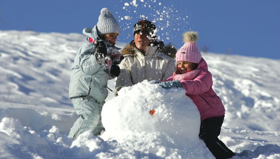 Kids making a snowman in Lapland, body of snowman almost finished